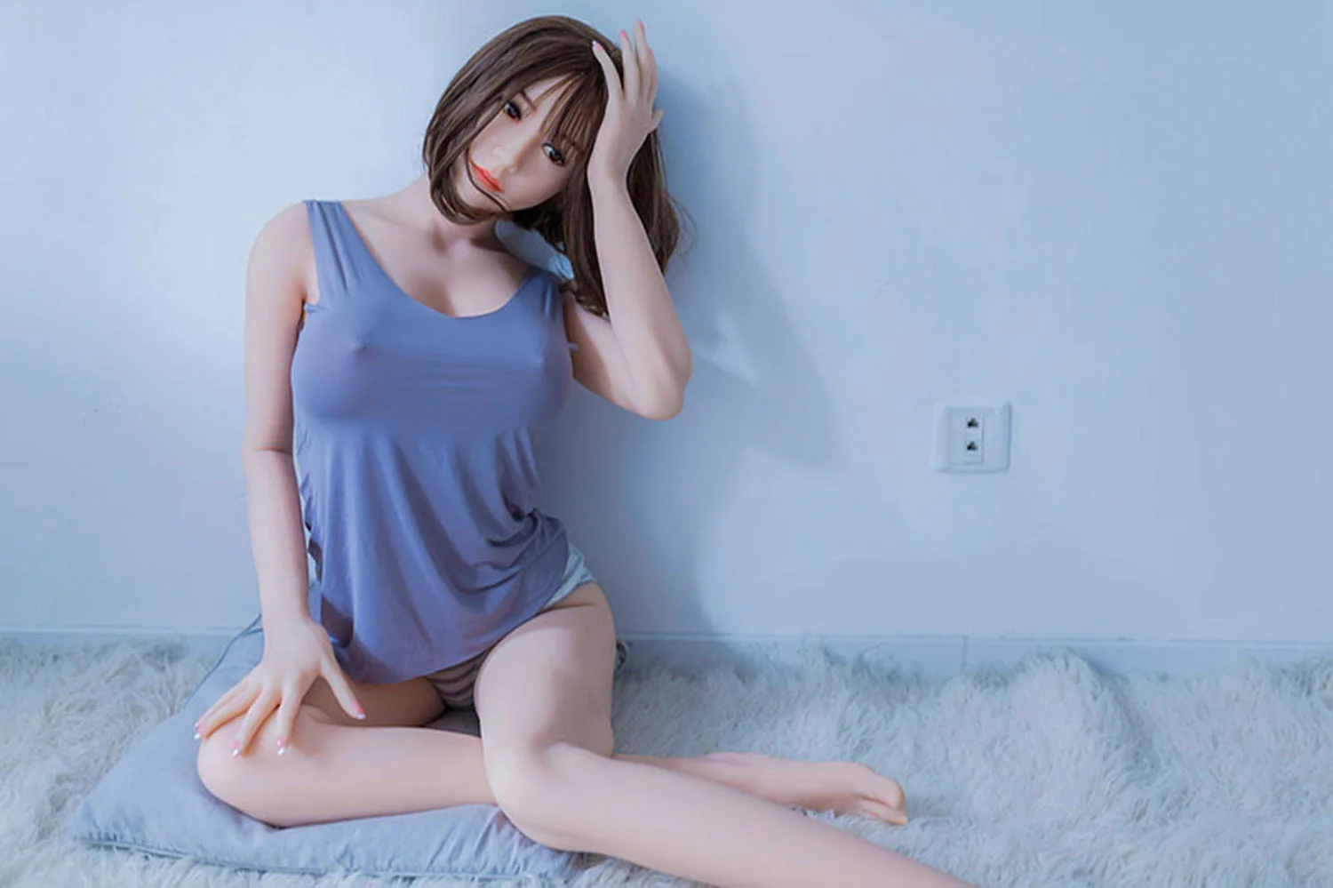 A sex doll sitting on the ground and touching her hair