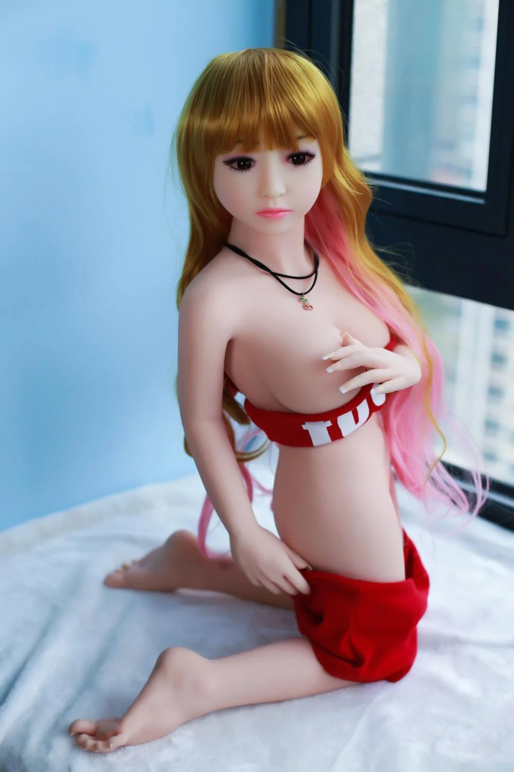 Mini sex doll with legs kneeling on the bed