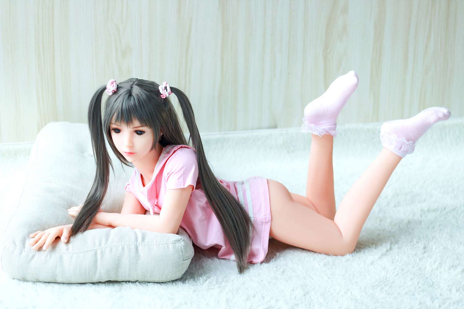A mini sex doll lying on the floor with legs raised