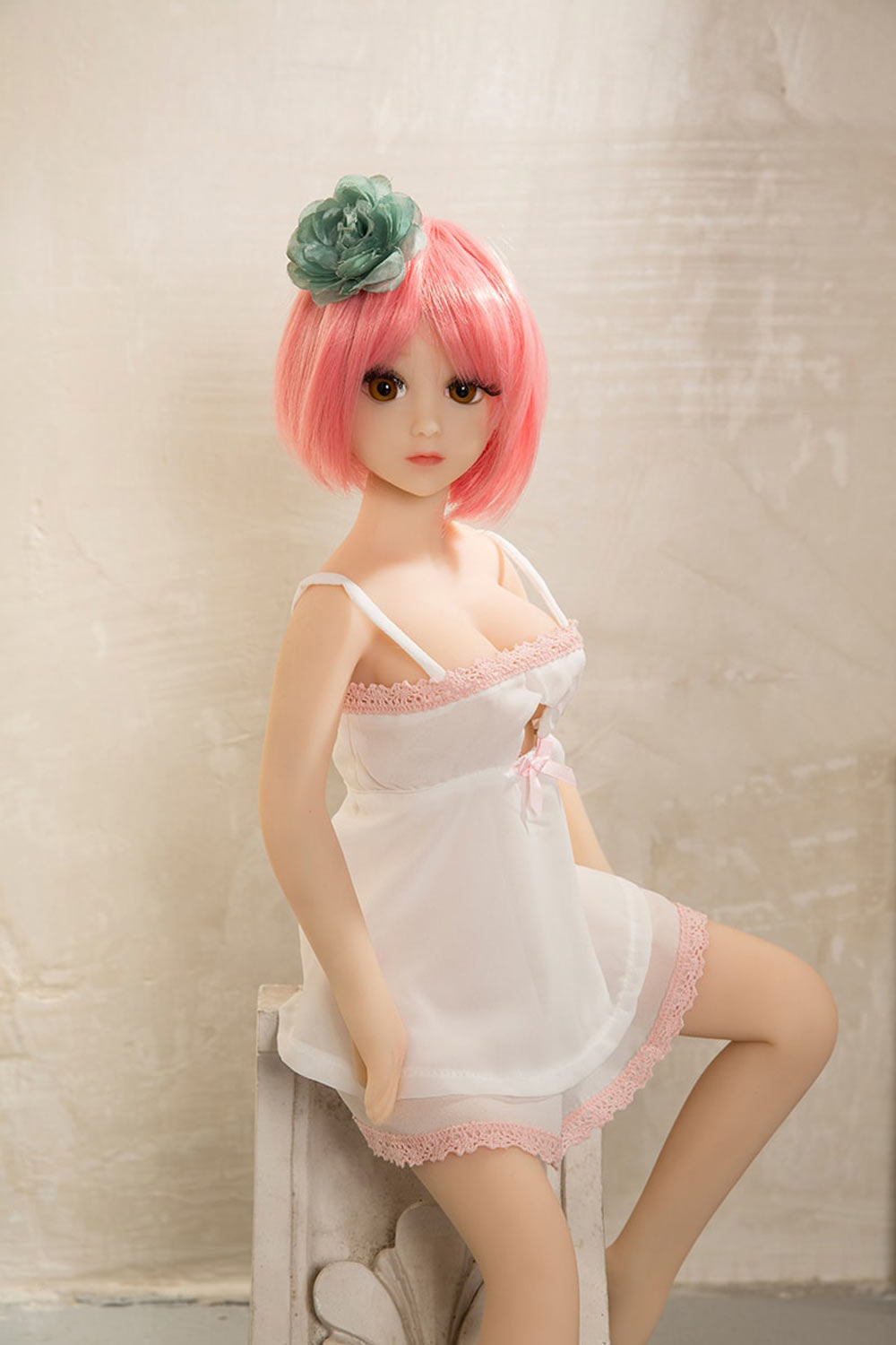 A mini sex doll with short pink hair in a white dress