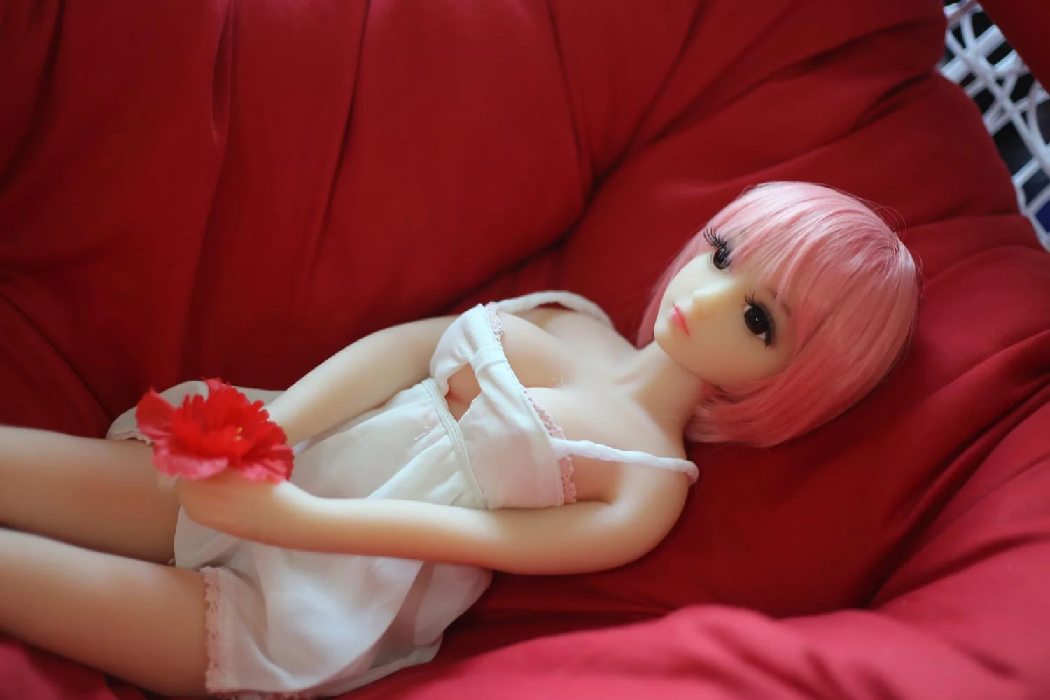 Mini sex doll lying down holding red flowers