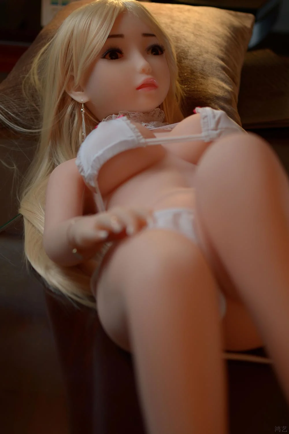 Mini sex doll lying on the bed with hands on thighs