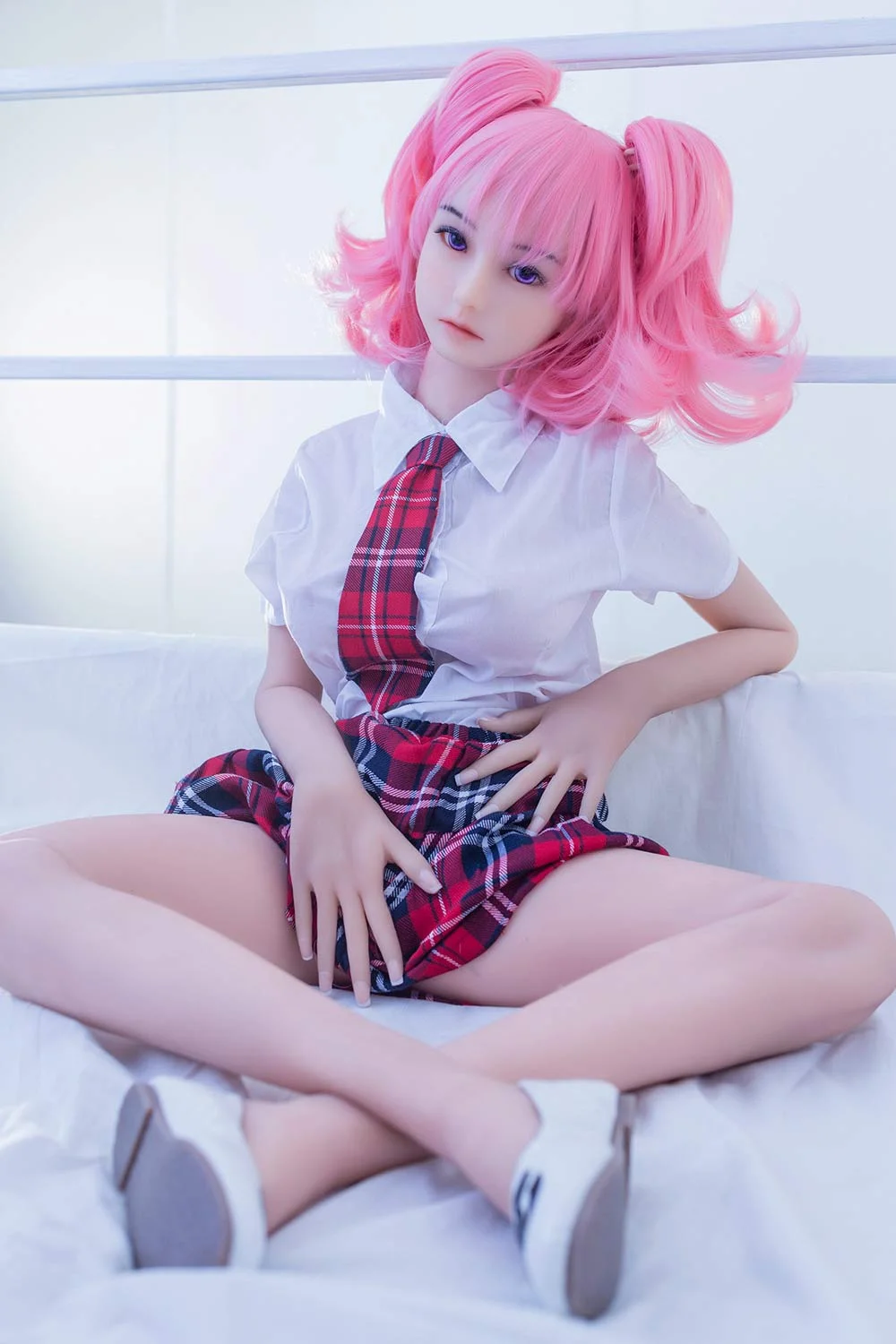 Mini sex doll sitting on the floor with legs crossed and touching skirt