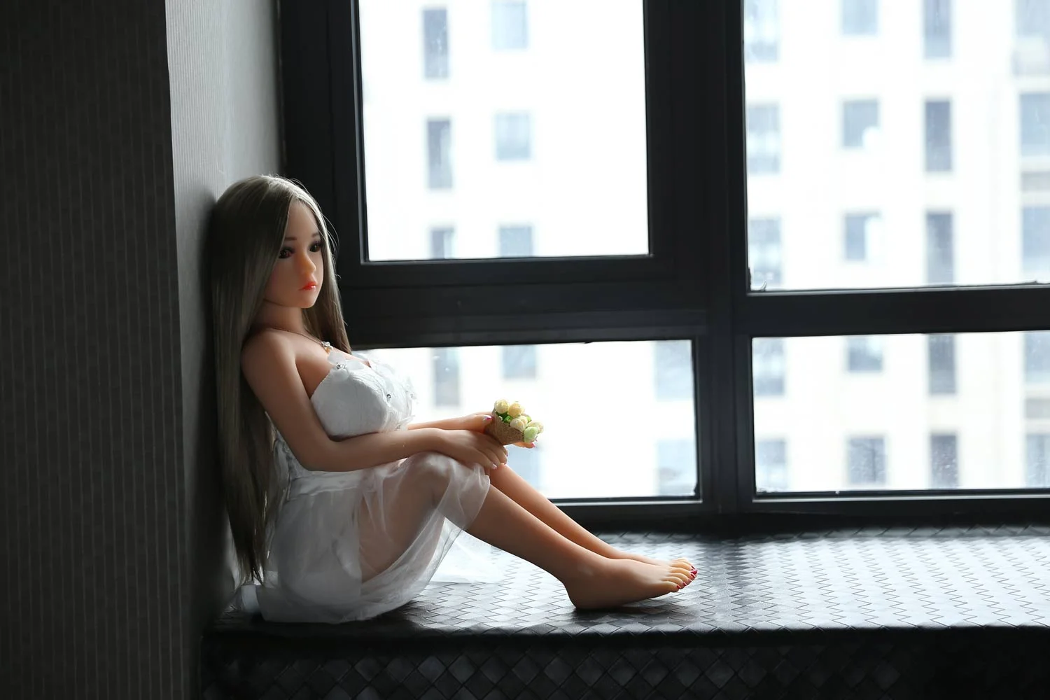Mini sex doll sitting on the windowsill