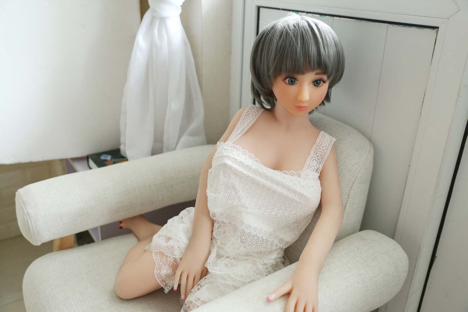 Mini sex doll with hands on the armrest of the sofa