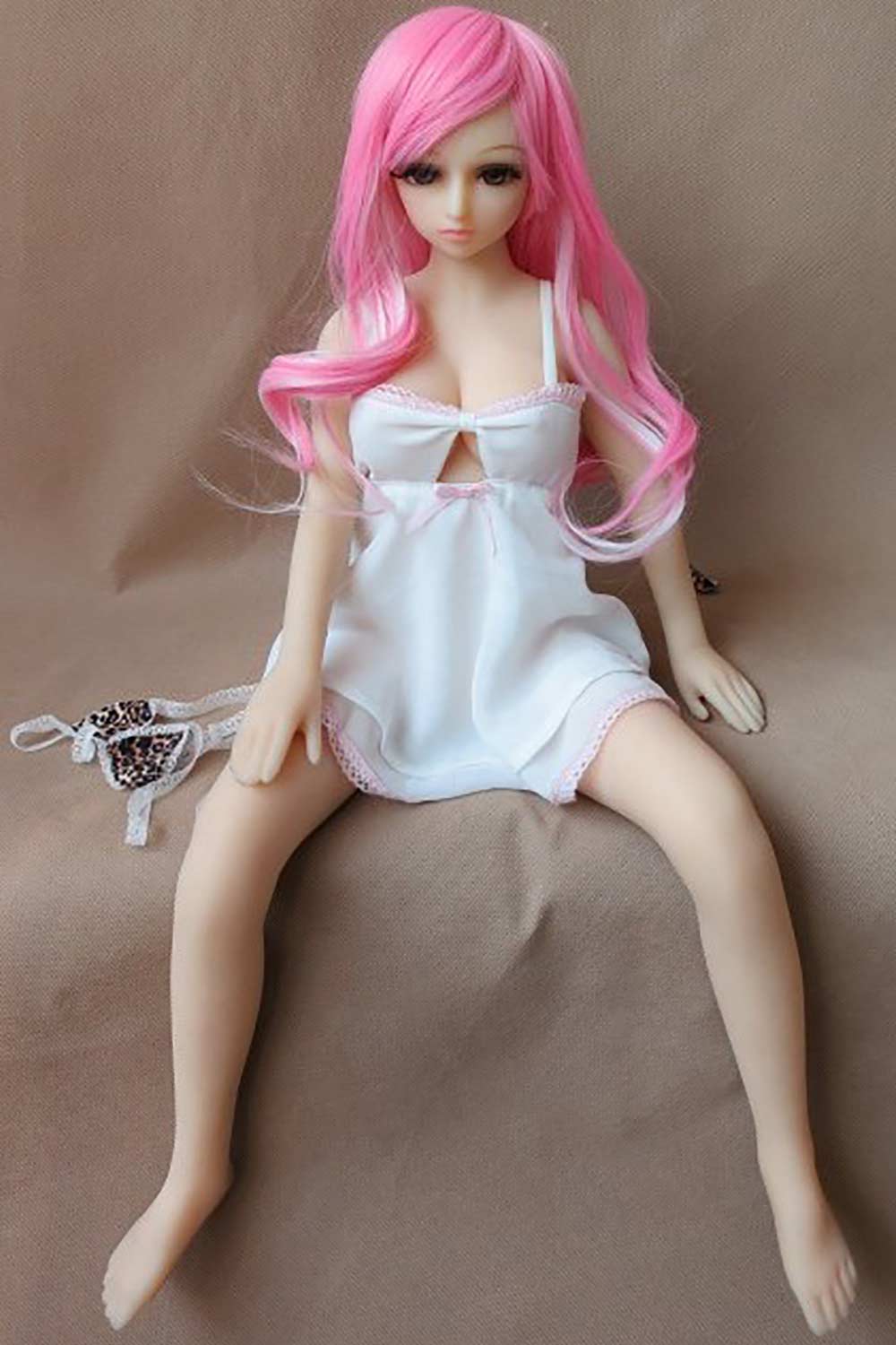 Mini sex doll with pink long hair and hands on legs