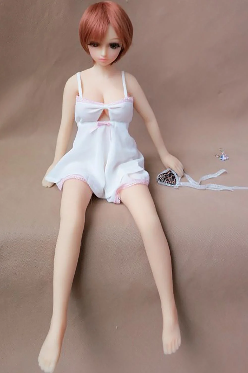 Mini sex doll with short brown hair sitting on the sofa