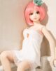 Mini sex doll with short pink hair leaning against the wall
