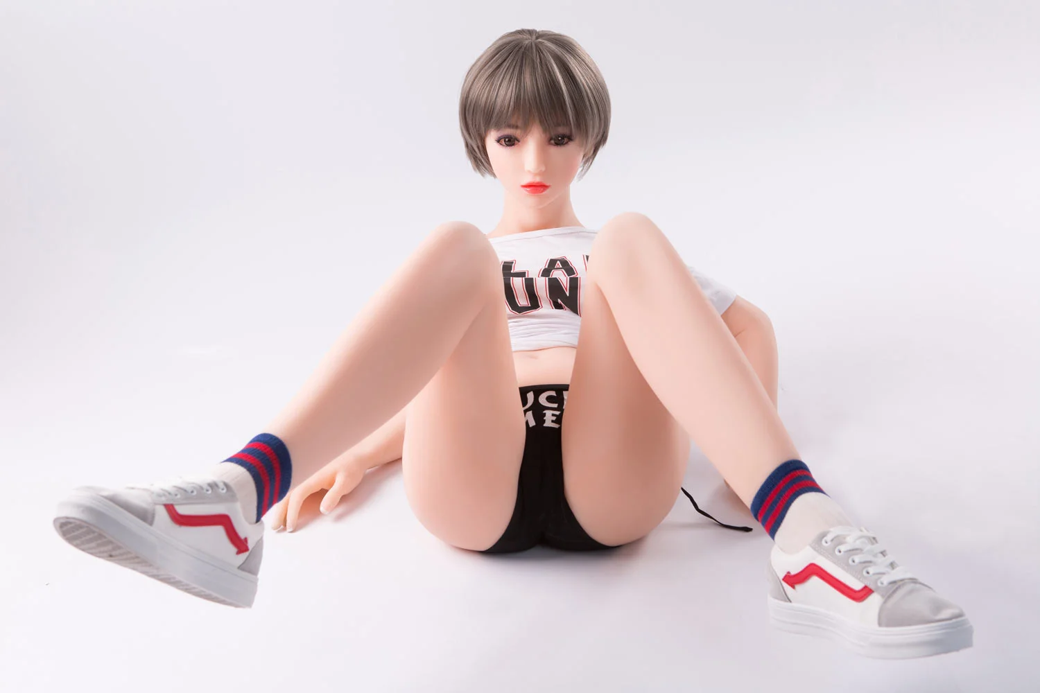 A mini sex doll lying on the ground with open legs