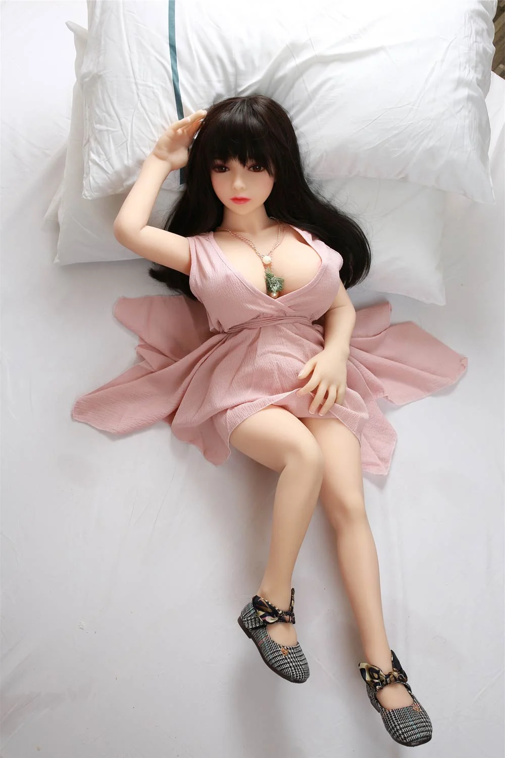 Mini sex doll lying on the bed in shoes