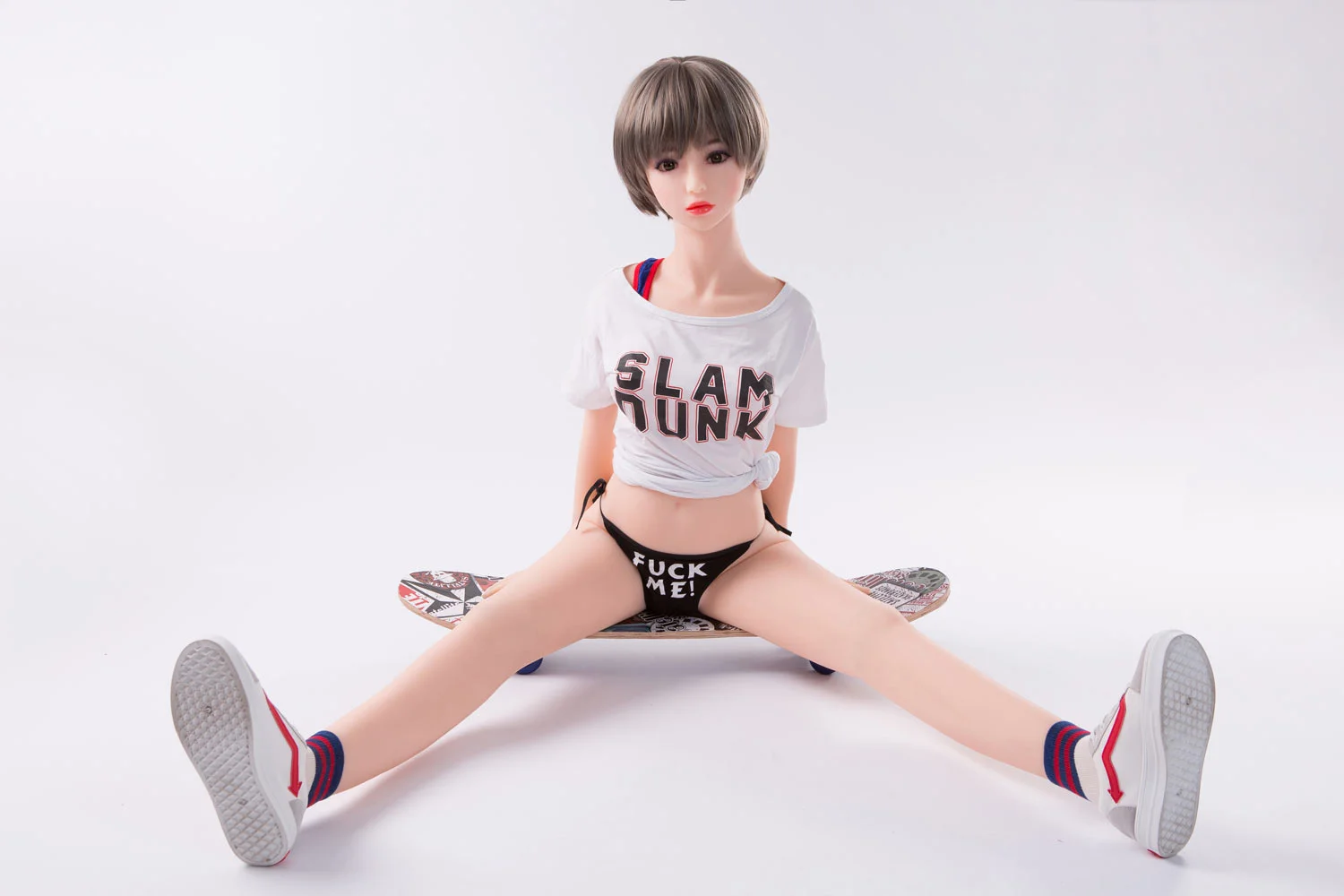 Mini sex doll sitting on a skateboard with open legs