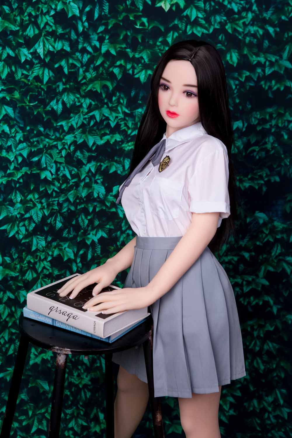 Mini sex doll with a book on a stool