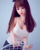 Mini sex doll with hands on the arm of the chair