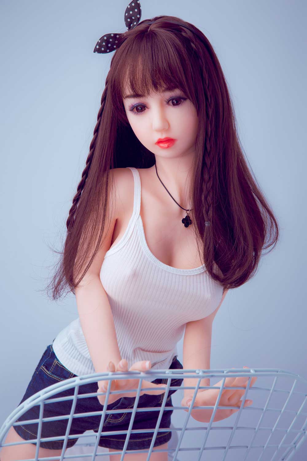 Mini sex doll with hands on the arm of the chair