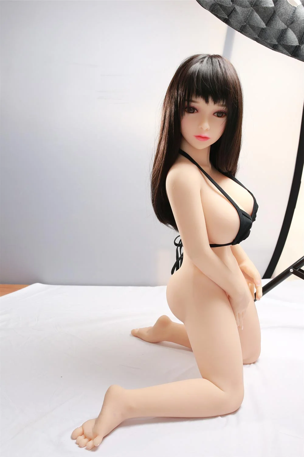Mini sex doll with legs kneeling on the ground and touching vagina