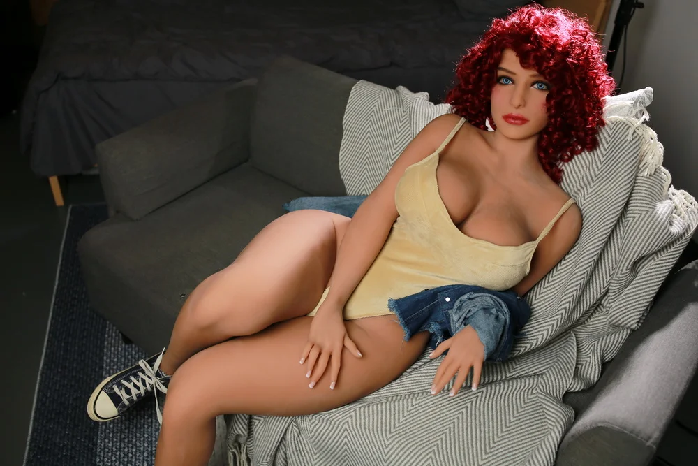 Big breasted sex doll lying on the sofa with hands on thighs