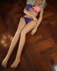 Sex doll lying on the floor with hands on abdomen