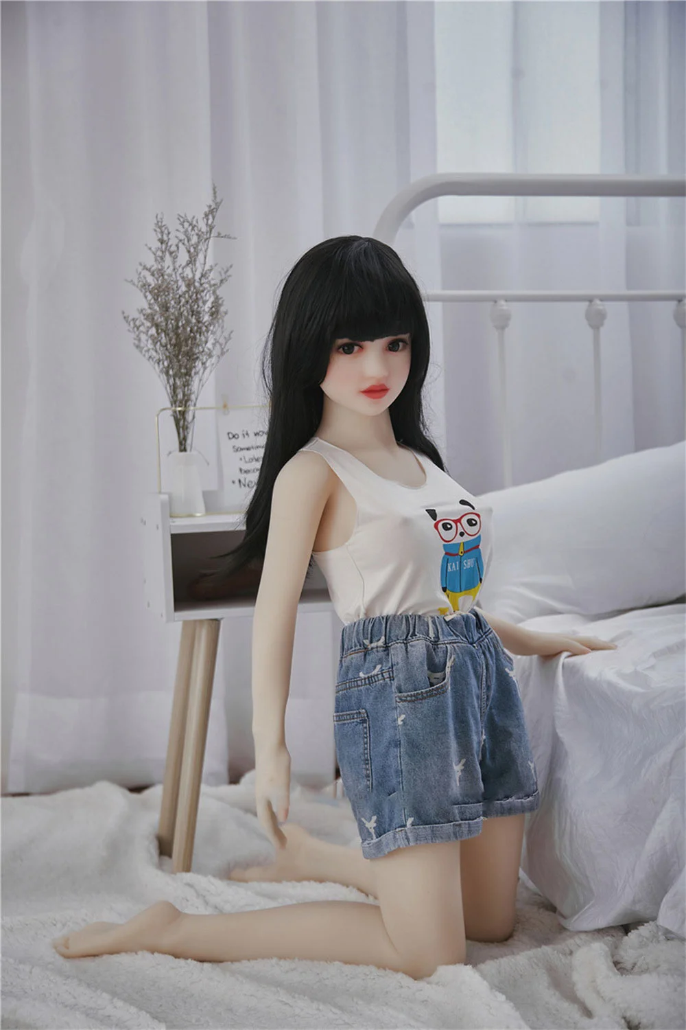 A mini sex doll kneeling on the ground with hands on the bed