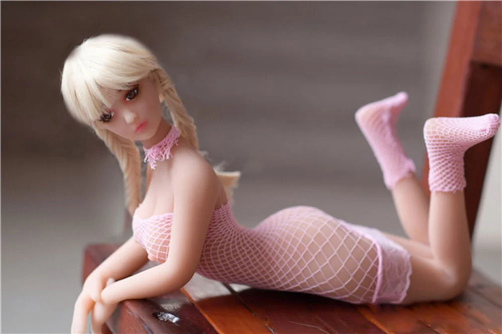 A mini sex doll lying on a chair and raising his legs