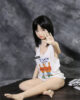 A mini sex doll sitting on the ground with her legs pressed