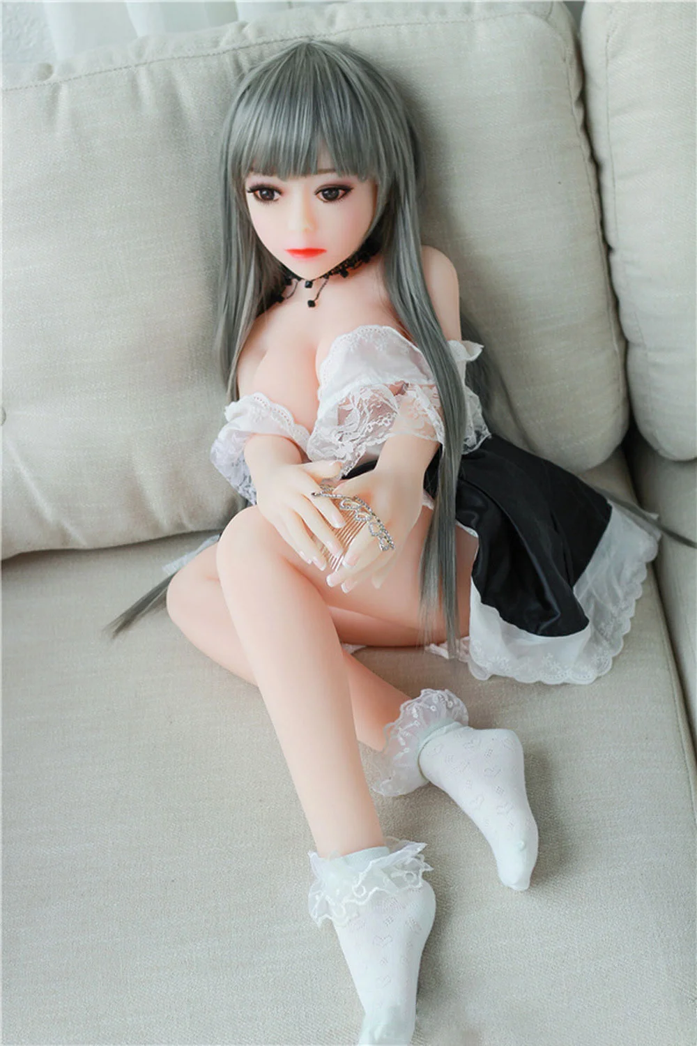 A mini sex doll with bent legs and hands on thighs