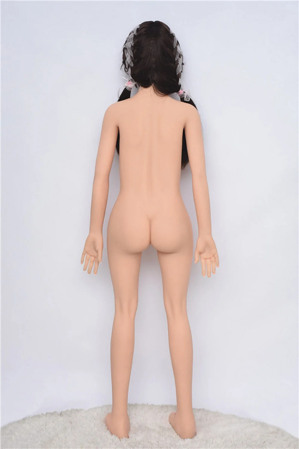 A sex doll standing naked and facing the wall