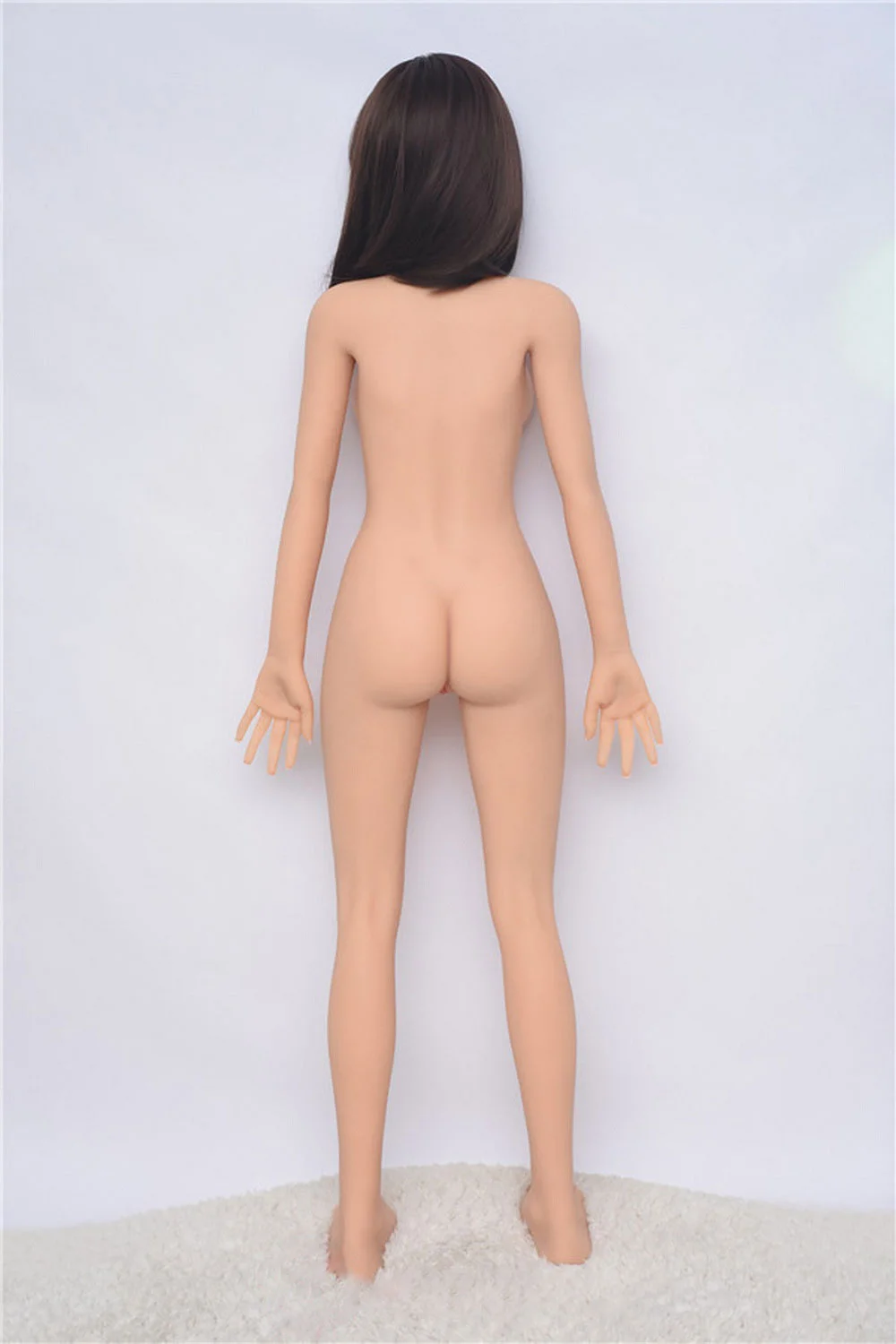 A sex doll with a naked body facing the wall