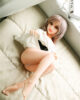Mini sex doll lying on the bed with legs bent