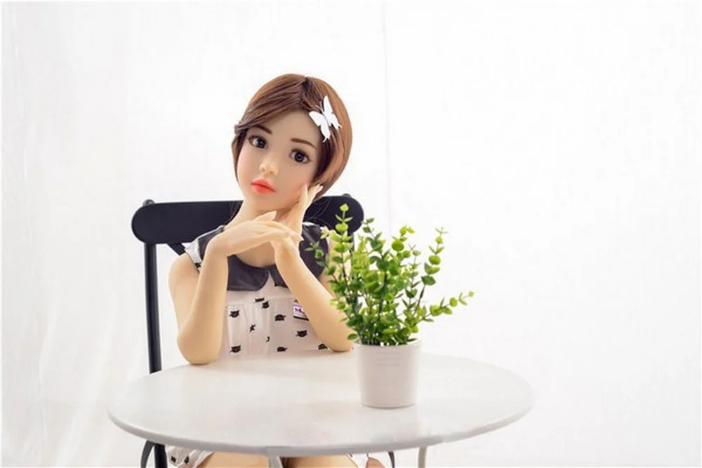 Mini sex doll with hands on the table