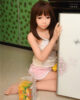 Sex doll kneeling on the ground with a drink next to it