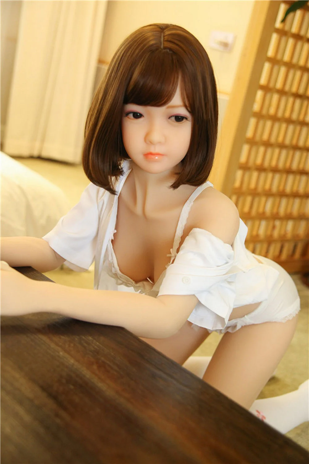 Sex doll kneeling on the ground with hands on the coffee table