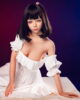 Silicone sex doll sitting on the table with hands on skirt